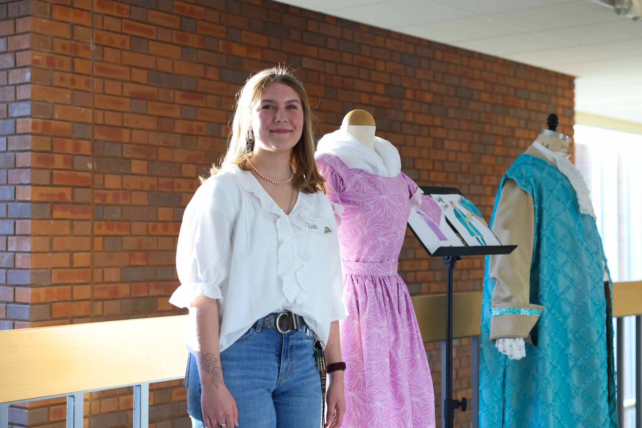 Theatre student standing by 2 theatre costumes
