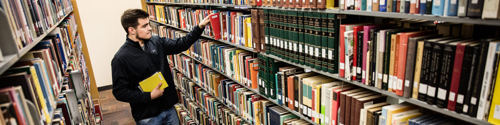 Student picking out books in the library