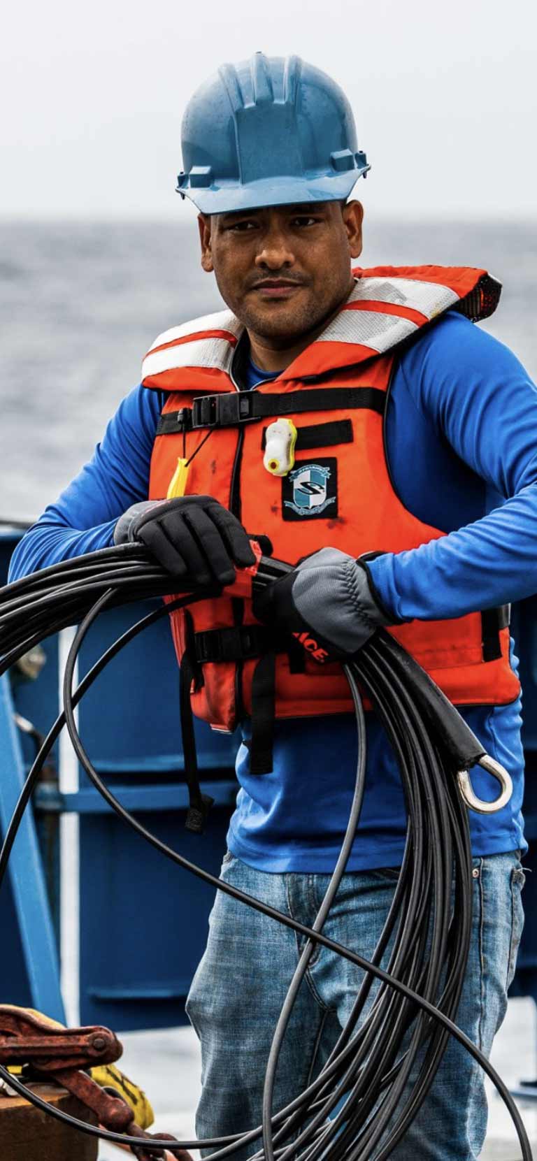 Photo of Wokil Bam holding a tether strap on a ship deck