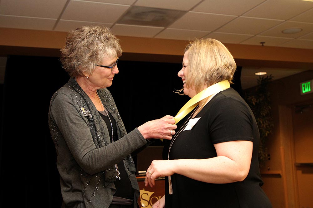 Laurie Johansen, left, pins an RN to BSN graduate. There are 150 alumni in the RN to BSN program.