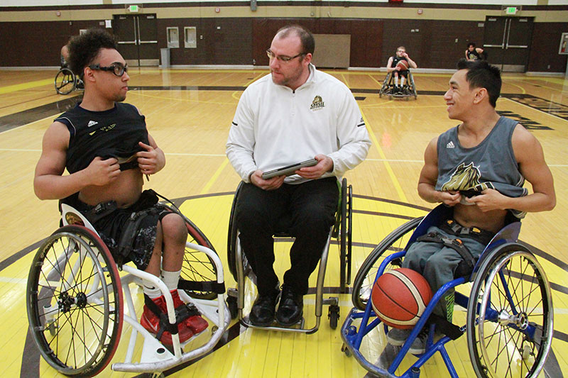 Players Ezekiel Ramudzi, left, and Nate Davis put on their heart monitors while coach Derek Klinkner prepares to have the data downloaded to his tablet.